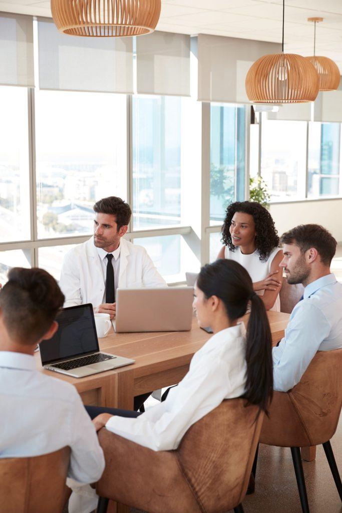 Pessoas sentadas à volta de uma mesa , com computadores à frente